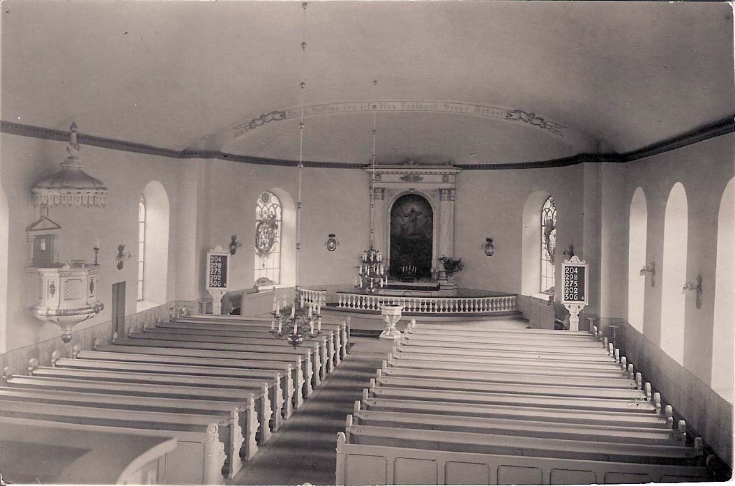Äldre kyrkointeriör med träbänkar, predikstol och altare