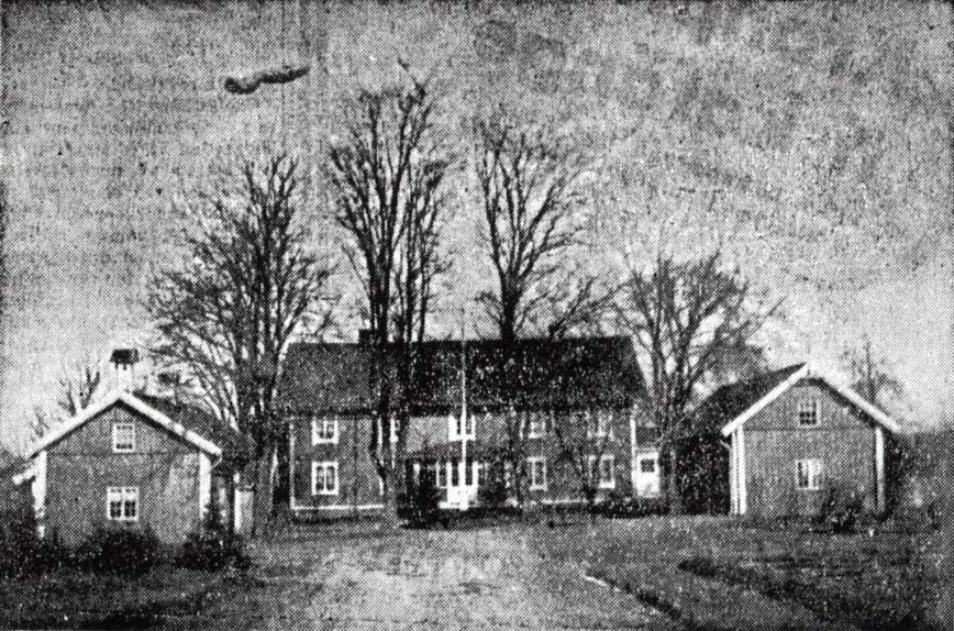 Äldre svartvit bild av en gård med huvudbyggnad och två mindre hus