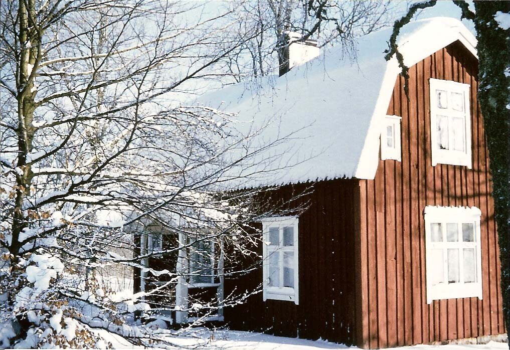 Rött äldre trähus med vita fönster i vinterlandskap